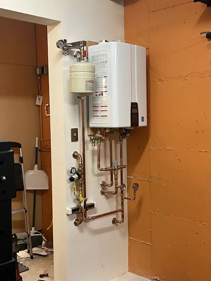 Plumbing technician inspecting water heater connections in Sussex